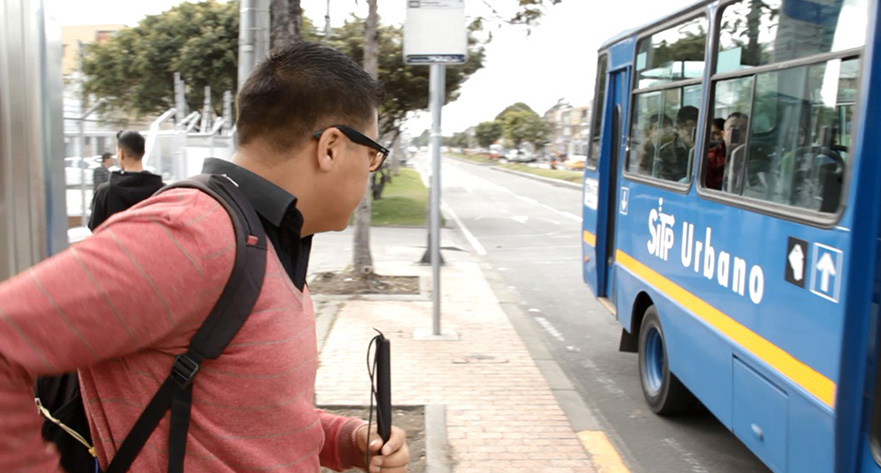 Imagen de persona con baja visión utilizando un bastón en un paradero de bus