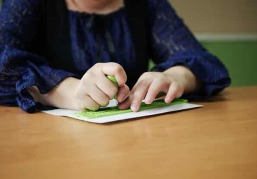 Plano cercano de un niño escribiendo en braile